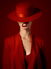 Image showing Woman, red aesthetic and makeup with hat, art and teeth out for couture, emoji and studio background. Girl, model and high fashion with suit, attitude and sexy with beauty, lipstick and cosmetics