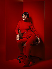 Image showing Beauty, fashion and woman on a chair with red background in studio for elegant, chic or trendy style. Aesthetic, art and confident with edgy or classy young person in unique clothes or suit at board