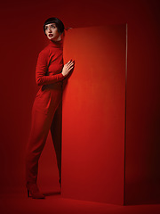 Image showing Beauty, fashion and a model woman on red background in studio for elegant, chic or trendy style. Aesthetic, art and confident with an edgy or classy young person in a unique clothes or suit at board