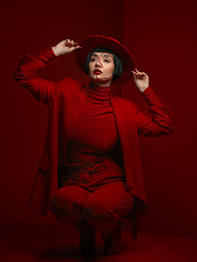 Image showing Woman, fashion and beauty with red aesthetic, makeup with art deco and vintage hat isolated on studio background. Retro style, female model with serious expression and cosmetics, attractive and bold