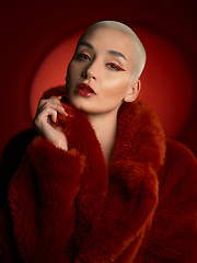 Image showing Fashion, portrait and serious woman in a red coat in studio isolated on a background. Face, makeup and confident bald model with cosmetics, aesthetic or style, trendy and fur clothes from Switzerland