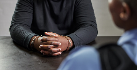 Image showing Criminal, hands and handcuffs and table for interrogation, questions or accusation with officer in room. Police talking to prisoner, gangster or thief for security, discussion or arrest in prison