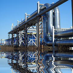 Image showing industrial pipelines on pipe-bridge against blue sky  with refle