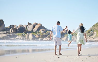 Image showing Family, parents and lifting a child at the beach for fun, adventure and play on holiday. Behind a woman, man and young kid walking on sand or swinging on vacation at the ocean, nature or outdoor