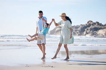 Image showing Family, mother and father with a child at the beach for fun, adventure and play on holiday. A happy woman, man and young kid walking on sand or swinging on vacation at the ocean, nature or outdoor