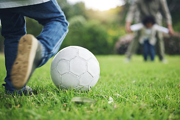 Image showing Child, legs and kick soccer ball on grass for fun activity, childhood or playing in the park. Playful little boy in sports game or match for score, point or goal on green field in the nature outdoors