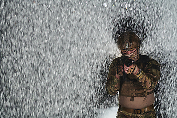 Image showing Army soldier in Combat Uniforms with an assault rifle, plate carrier and combat helmet going on a dangerous mission on a rainy night.