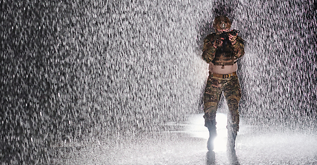 Image showing Army soldier in Combat Uniforms with an assault rifle, plate carrier and combat helmet going on a dangerous mission on a rainy night.