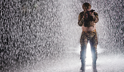 Image showing Army soldier in Combat Uniforms with an assault rifle, plate carrier and combat helmet going on a dangerous mission on a rainy night.