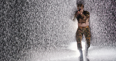 Image showing Army soldier in Combat Uniforms with an assault rifle, plate carrier and combat helmet going on a dangerous mission on a rainy night.