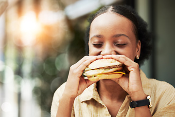 Image showing Happy, fast food and black woman eating a sandwich in an outdoor restaurant as a lunch meal craving deal. Breakfast, burger and young female person or customer enjoying a tasty unhealthy snack