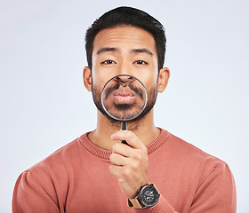 Image showing Mouth, portrait of a man with a magnifying glass in hand on a white studio background for investigation. Face of Asian person or model with a magnifier to show lips or zoom for inspection or emoji
