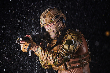 Image showing Army soldier in Combat Uniforms with an assault rifle, plate carrier and combat helmet going on a dangerous mission on a rainy night.