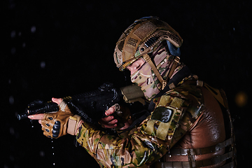 Image showing Army soldier in Combat Uniforms with an assault rifle, plate carrier and combat helmet going on a dangerous mission on a rainy night.