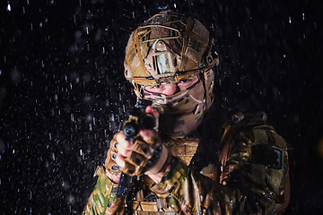 Image showing Army soldier in Combat Uniforms with an assault rifle, plate carrier and combat helmet going on a dangerous mission on a rainy night.