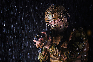 Image showing Army soldier in Combat Uniforms with an assault rifle, plate carrier and combat helmet going on a dangerous mission on a rainy night.