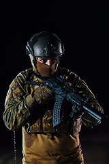 Image showing A professional soldier in full military gear striding through the dark night as he embarks on a perilous military mission