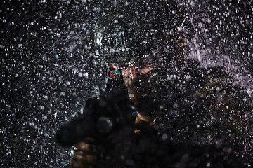 Image showing Army soldier in Combat Uniforms with an assault rifle, plate carrier and combat helmet going on a dangerous mission on a rainy night.