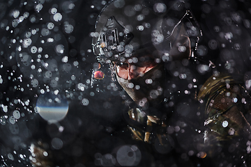 Image showing Army soldier in Combat Uniforms with an assault rifle, plate carrier and combat helmet going on a dangerous mission on a rainy night.