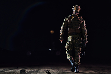 Image showing A professional soldier in full military gear striding through the dark night as he embarks on a perilous military mission