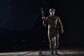 Image showing A professional soldier in full military gear striding through the dark night as he embarks on a perilous military mission