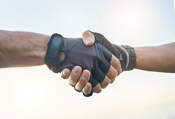 Image showing Teamwork, cycling and sports men shaking hands outdoor together against a sky background with flare. Handshake, fitness and partnership with a cyclist team saying thank you during a cardio workout