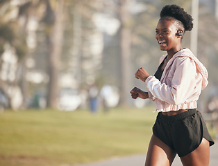 Image showing Black woman, fitness and running outdoor with earphones for listening to music, radio or podcast. Sports, smile and happy African athlete training, workout and exercise for health, wellness or cardio