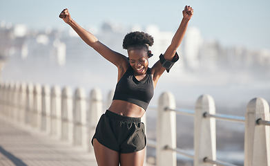 Image showing Happy woman, dance and fitness success by city beach in energy, exercise and cardio health with music technology. Listening, training and celebration, winning or yes of african person or runner goals