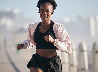 Image showing Portrait, running and black woman outdoor with earphones for audio, radio music and podcast. Sports, fitness and happy African athlete training, workout and exercise for health, wellness and cardio