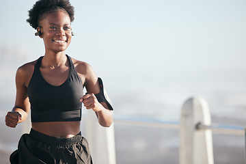 Image showing Smile, running and black woman outdoor with music earphones for radio, podcast and mockup space. Sports, fitness and happy African athlete training, workout or exercise for health, wellness or cardio