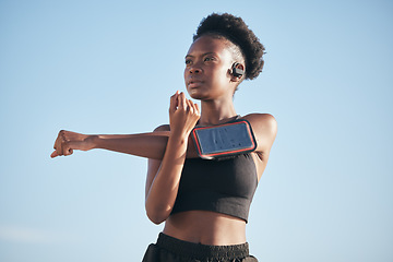 Image showing Fitness, music and stretching with a black woman runner outdoor on a blue sky for cardio or endurance training. Exercise, body or phone with a young athlete getting ready for a sports workout