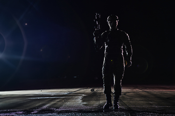 Image showing A professional soldier in full military gear striding through the dark night as he embarks on a perilous military mission