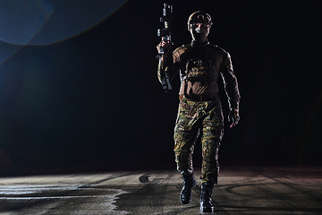 Image showing A professional soldier in full military gear striding through the dark night as he embarks on a perilous military mission