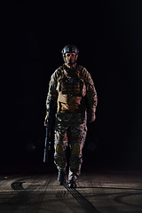 Image showing A professional soldier in full military gear striding through the dark night as he embarks on a perilous military mission