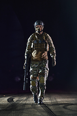 Image showing A professional soldier in full military gear striding through the dark night as he embarks on a perilous military mission