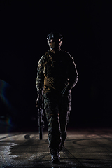 Image showing A professional soldier in full military gear striding through the dark night as he embarks on a perilous military mission