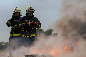 Image showing Firefighters fight the fire flame to control fire not to spreading out. Firefighter industrial and public safety concept. Traffic or car accident rescue and help action.