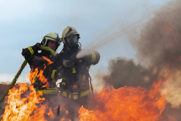 Image showing Firefighters fight the fire flame to control fire not to spreading out. Firefighter industrial and public safety concept. Traffic or car accident rescue and help action.