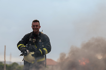 Image showing Portrait of a heroic fireman in a protective suit. Firefighter in fire fighting operation.