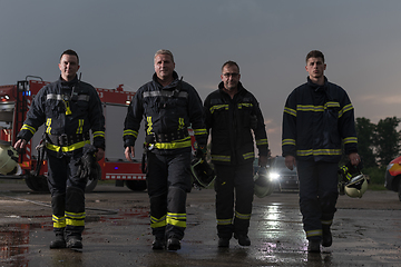 Image showing Brave Firefighters Team Walking to the Camera. In Background Paramedics and Firemen Rescue Team Fight Fire in Car Accident, Insurance and Save Peoples Lives concept.