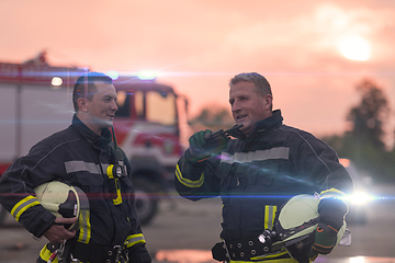 Image showing Fireman using walkie talkie at car traffic rescue action fire truck and fireman's team in background.