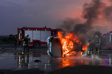 Image showing Firefighters fight the fire flame to control fire not to spreading out. Firefighter industrial and public safety concept. Traffic or car accident rescue and help action.