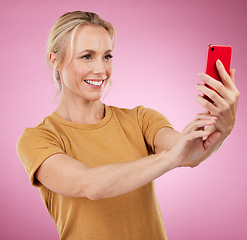 Image showing Selfie, happy and woman with a phone in the studio with a positive, optimistic and good mindset. Happiness, smile and female model from Canada taking a picture on a cellphone by a pink background.