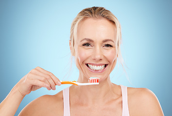 Image showing Woman, toothbrush and smile with teeth for dental care, dentist or oral hygiene against a blue studio background. Portrait of happy mature female smiling in satisfaction for mouth or gum treatment