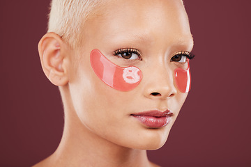 Image showing Portrait, eye mask and beauty with a model black woman posing in studio on a red background for skincare. Face, skin and antiaging with an attractive young female posing to promote a cosmetic product
