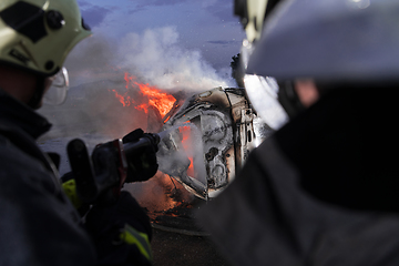 Image showing Firefighters fight the fire flame to control fire not to spreading out. Firefighter industrial and public safety concept. Traffic or car accident rescue and help action.