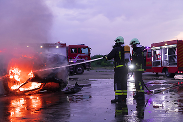 Image showing Firefighters fight the fire flame to control fire not to spreading out. Firefighter industrial and public safety concept. Traffic or car accident rescue and help action.