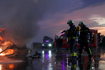 Image showing Firefighters fight the fire flame to control fire not to spreading out. Firefighter industrial and public safety concept. Traffic or car accident rescue and help action.