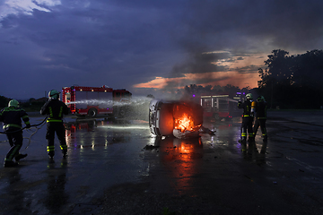 Image showing Firefighters fight the fire flame to control fire not to spreading out. Firefighter industrial and public safety concept. Traffic or car accident rescue and help action.