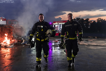 Image showing Brave Firefighters Team Walking to the Camera. In Background Paramedics and Firemen Rescue Team Fight Fire in Car Accident, Insurance and Save Peoples Lives concept.